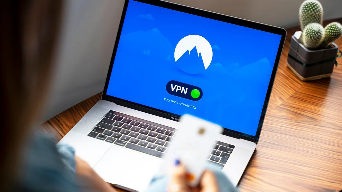Persoon bekijkt privacy-instellingen op een laptop met een telefoon ernaast