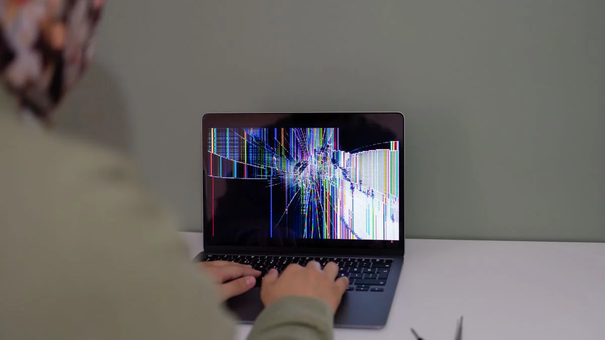 Persoon die achter een bureau het scherm van een laptop bekijkt