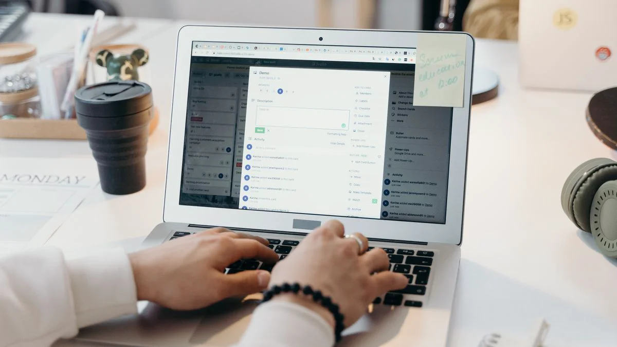 Kantoormedewerker bekijkt een verdacht bericht op een laptop terwijl een telefoon op het bureau ligt
