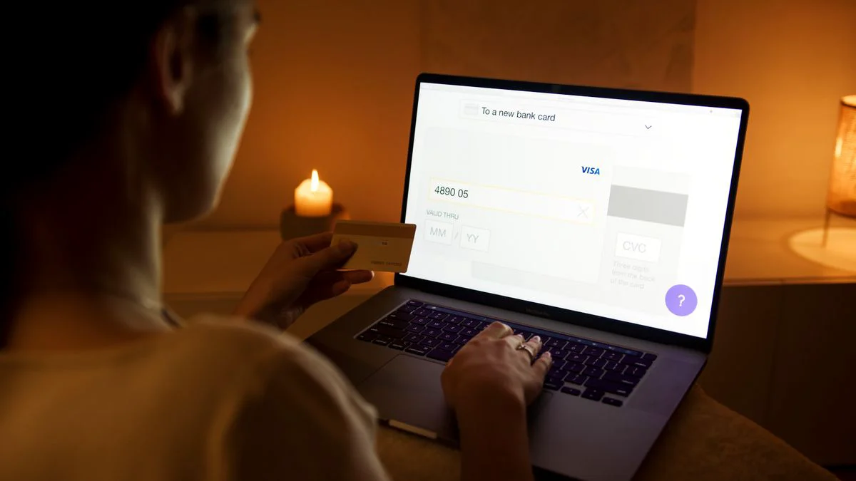 Persoon controleert banktransacties op een laptop met een telefoon ernaast