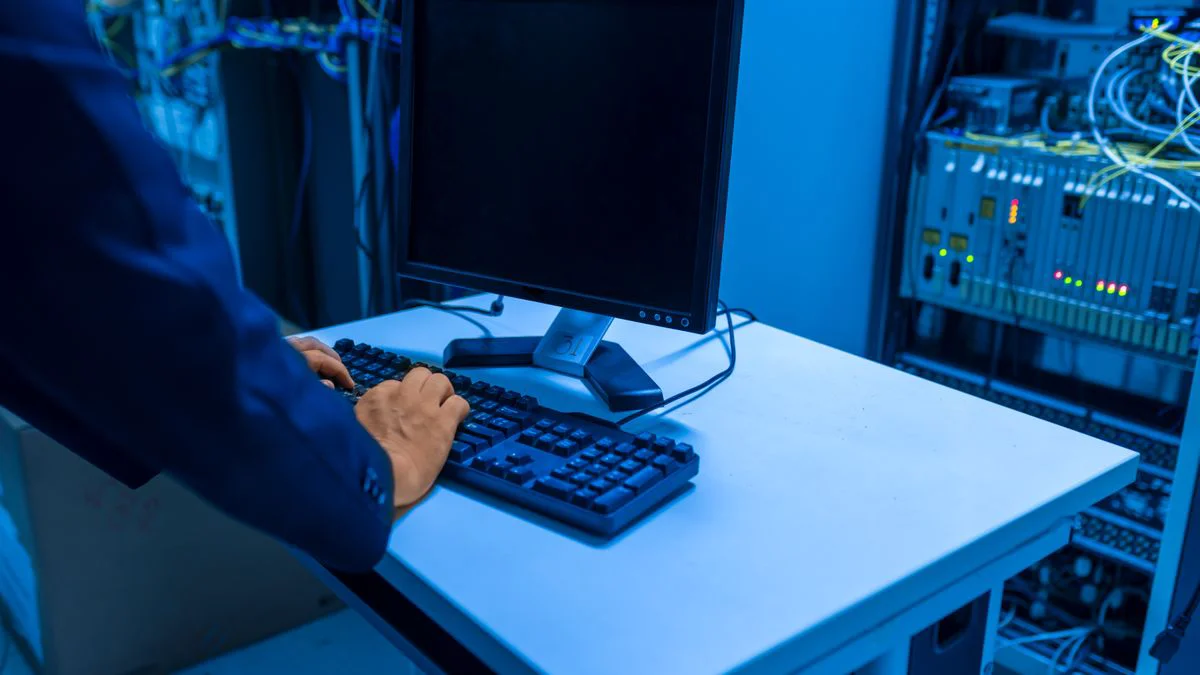 Technicus die met een laptop naast serverkasten werkt