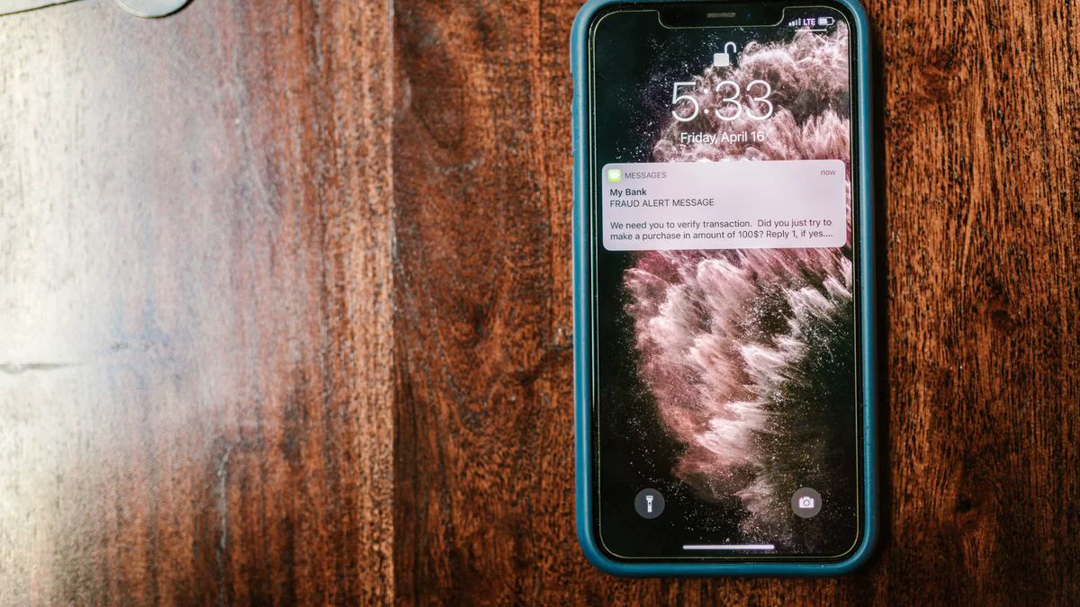 Smartphone met een verdacht bezorgbericht op het scherm naast een pakketdoos