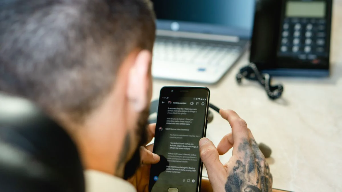 Smartphone met verdacht bericht naast een geopend e-mailvenster